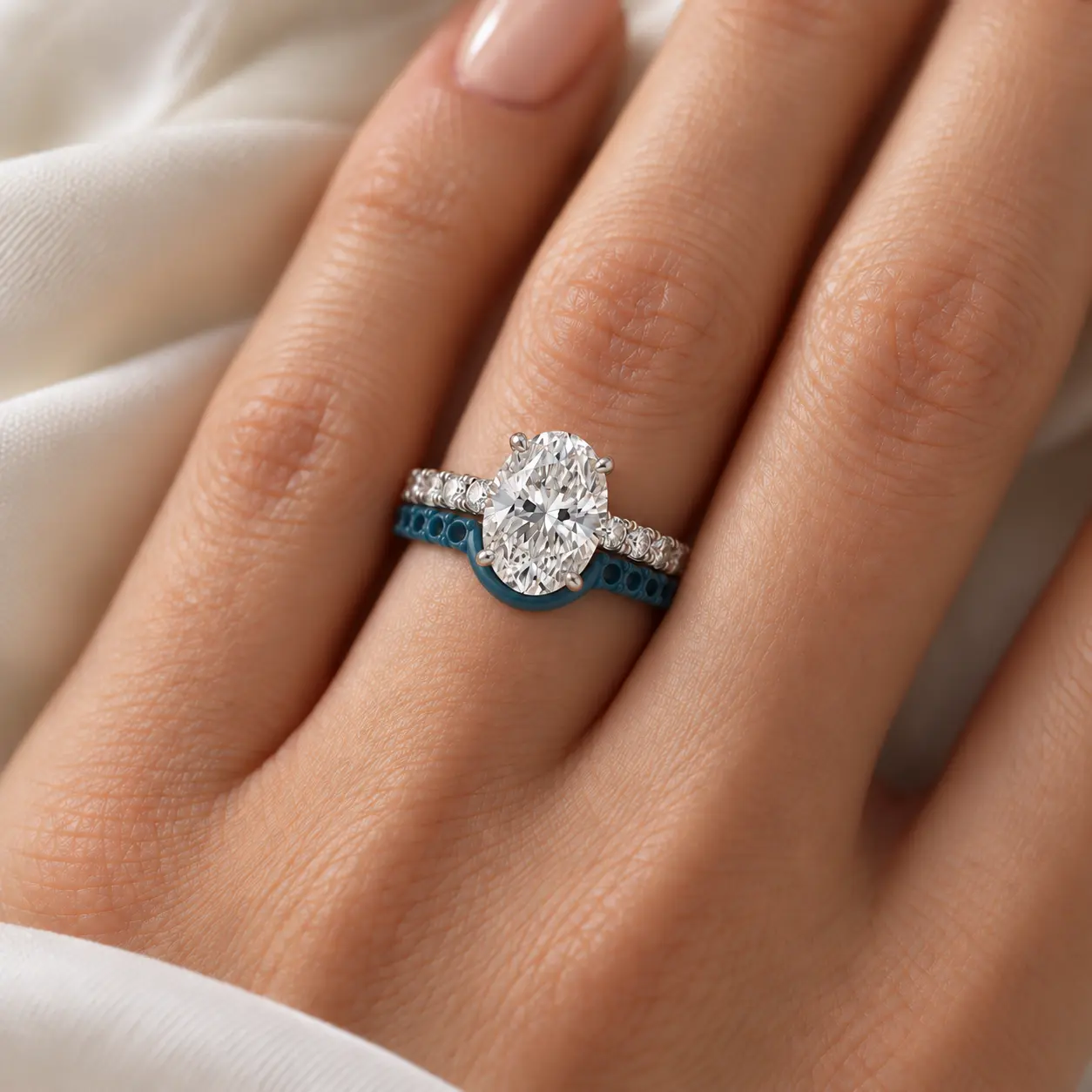 A blue wax prototype of a curved wedding band fitted closely beside an oval diamond engagement ring